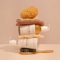Charger l'image dans la visionneuse de la galerie, Patomia Bark Bliss dog shampoo and conditioner bottles stacked with a natural sponge, towel, and wooden grooming brush.