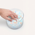 Charger l'image dans la visionneuse de la galerie, Patomia dog bed recycled foam filling in a glass bowl with a hand pressing into the soft, colorful foam pieces