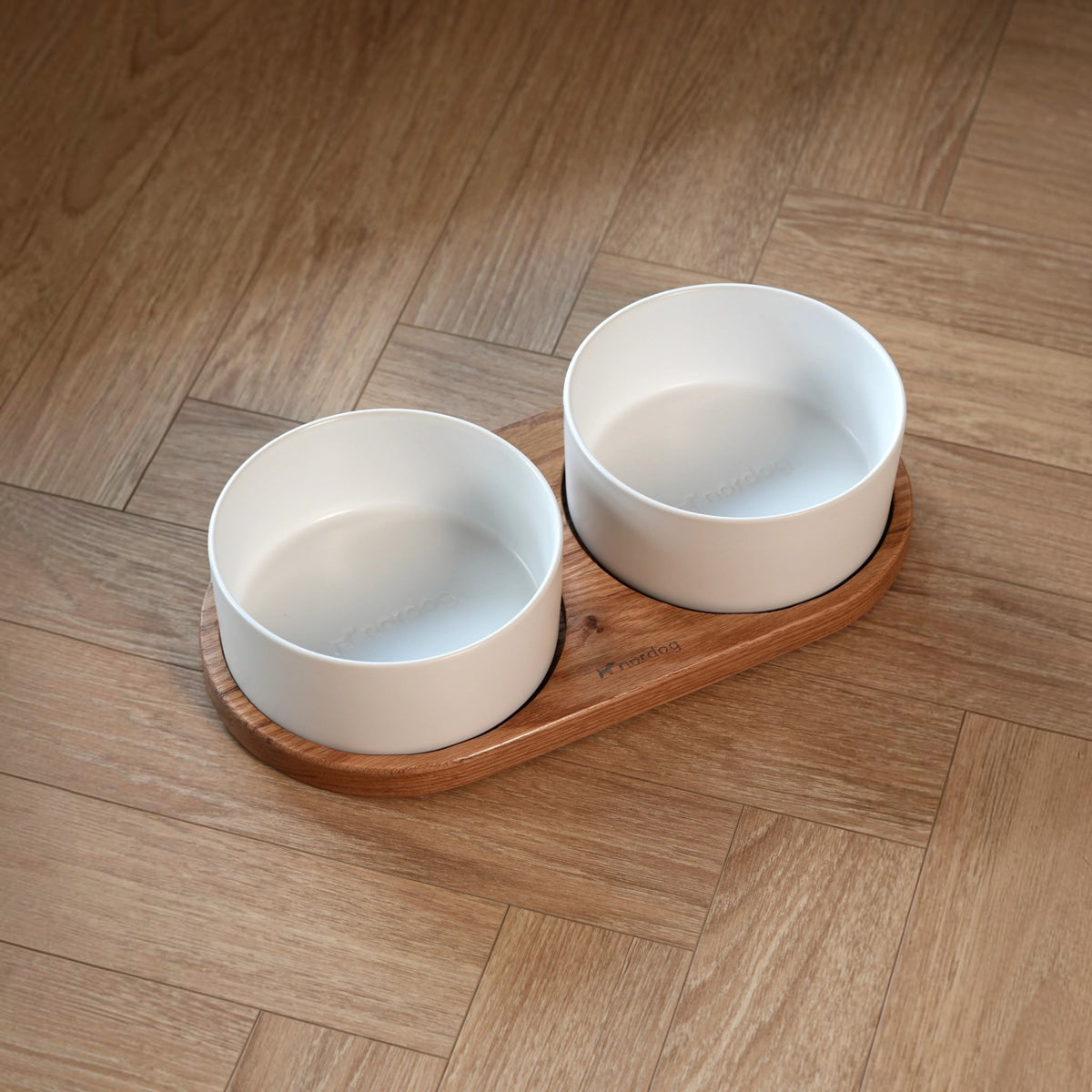 Patomia Barcelona double dog bowl with white ceramic bowls on an oiled oak wooden stand on a herringbone floor