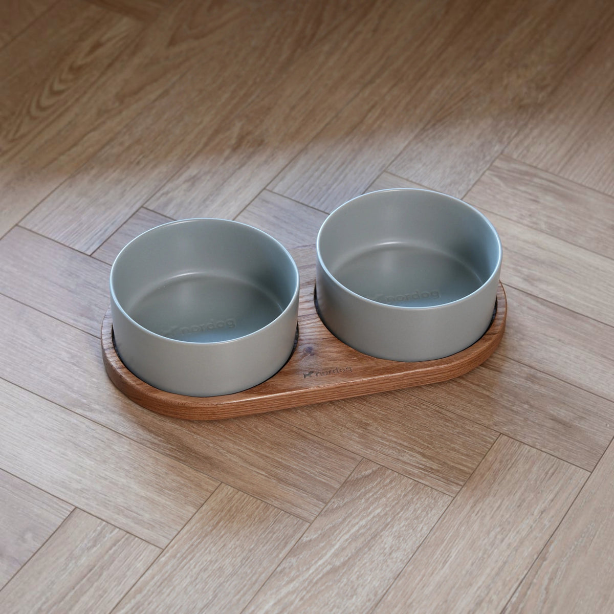 Patomia Barcelona double dog bowl set with an oiled oak wooden base and two grey ceramic bowls on a wooden floor