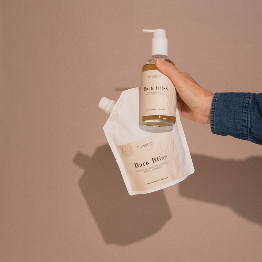 Patomia Pawness Bark Bliss nourishing dog shampoo bottle and refill pouch held by a hand against a neutral background