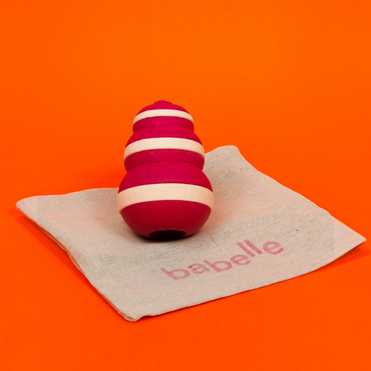 Patomia Bubble dog treat dispenser toy in pink and cream silicone on a small fabric bag against an orange background