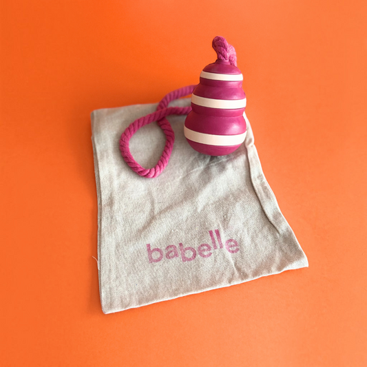 Patomia Bubble Feeder dog toy in pink and white silicone with a rope, resting on a branded beige fabric pouch.