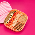 Charger l'image dans la visionneuse de la galerie, Patomia coral silicone lick mat with textured wavy surface filled with healthy pet food on a bright pink background

