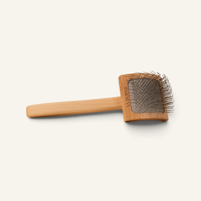 Patomia curved slicker brush with a beechwood handle and metal pins for detangling long, curly dog coats.
