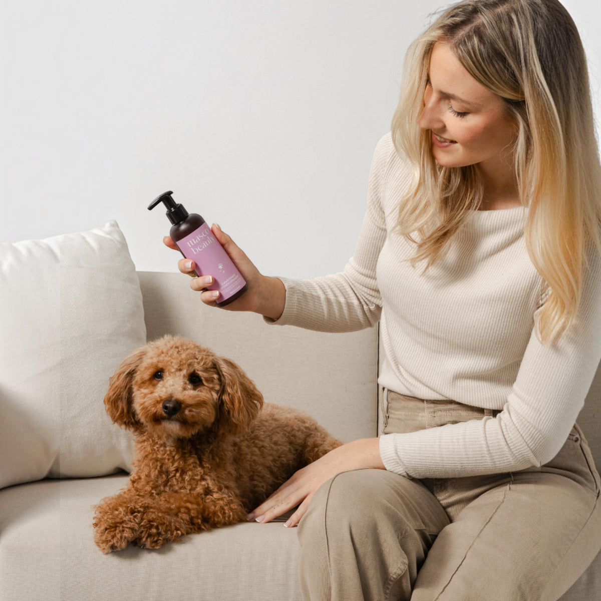 Patomia detangling conditioner for dogs and cats with long or curly hair, held by a woman next to a poodle