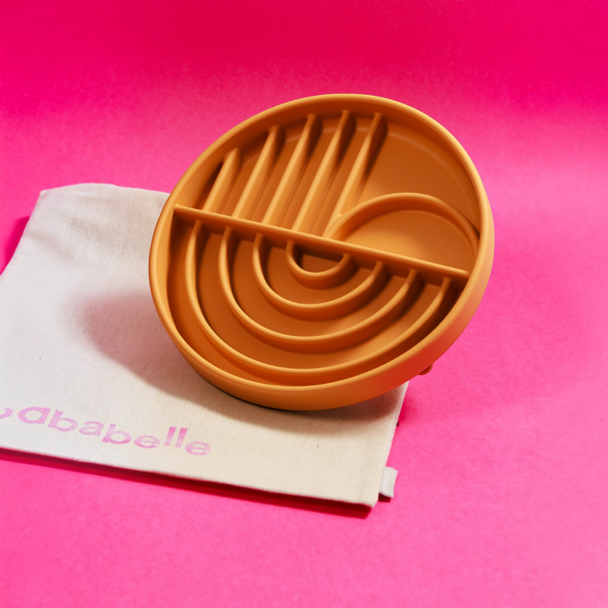 Patomia Dreamy round ochre silicone lick mat for dogs with arch patterns on a bright pink background