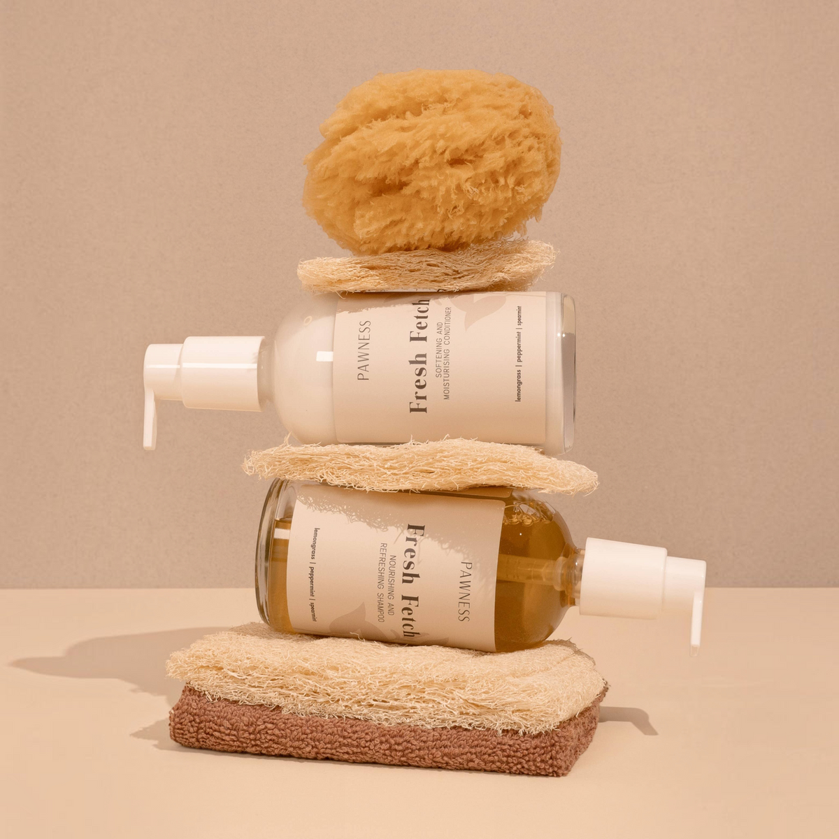 Patomia Fresh Fetch dog conditioner and shampoo bottles stacked with natural sponges on a beige background