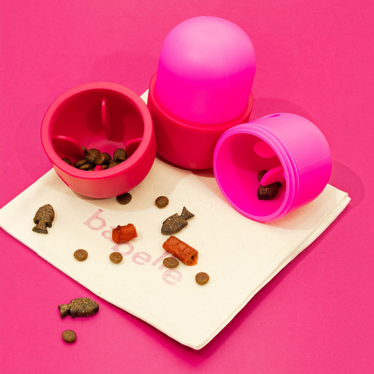 Patomia interactive treat dispenser toy in pink and red food-grade rubber, shown open with dry pet treats.