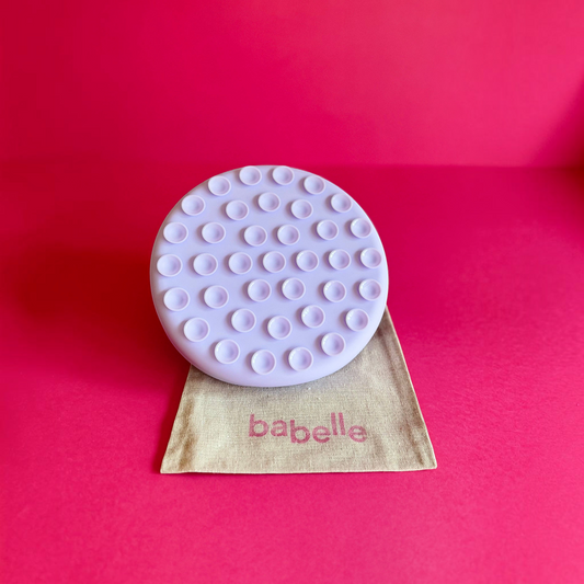Patomia The Petal lilac silicone dog lickmat with suction cups on a beige fabric pouch against a vibrant pink background
