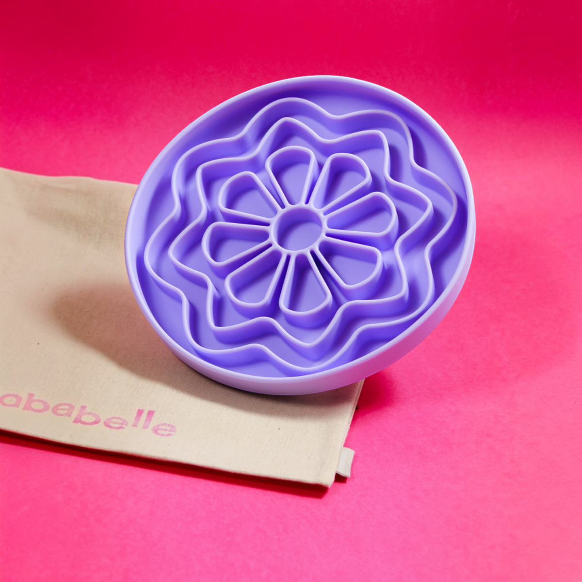 Patomia The Petal lilac silicone lickmat for dogs with a daisy-inspired design on a bright pink background.