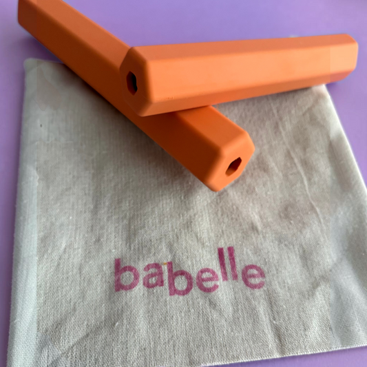 Patomia orange hexagonal treat tube enrichment toy for dogs resting on a branded fabric pouch