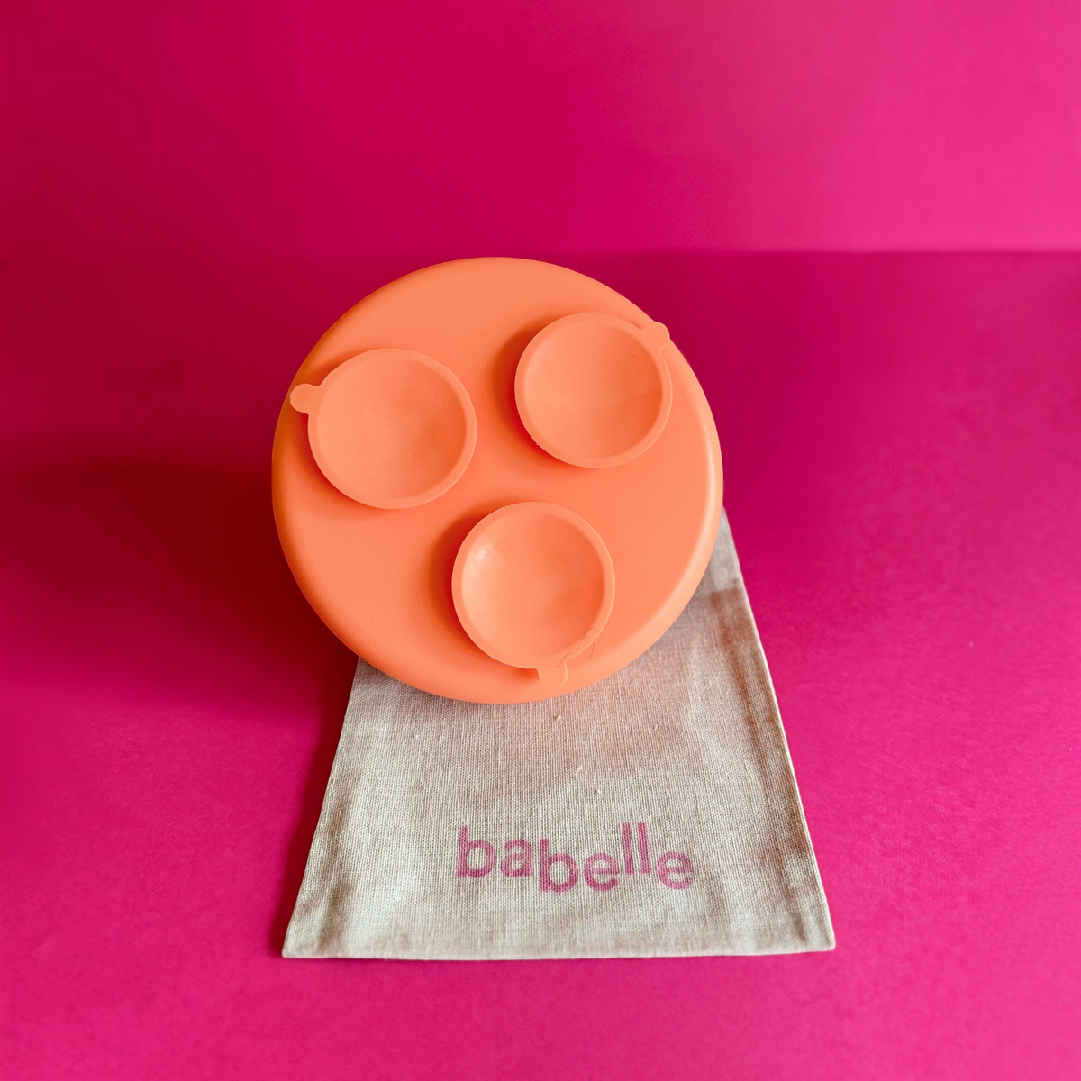 Patomia The Dreamy orange silicone lickmat for pets with suction cups on a beige fabric bag against a pink background