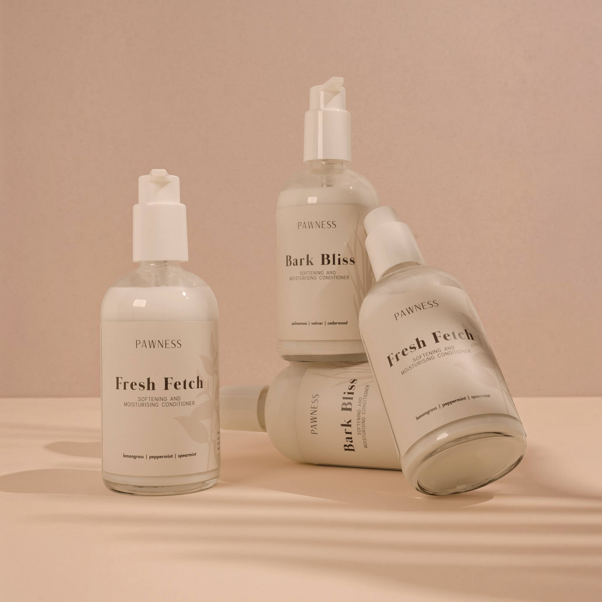 Patomia collection of Pawness Fresh Fetch and Bark Bliss dog conditioners in clear pump bottles on a beige background.