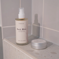 Charger l'image dans la visionneuse de la galerie, Patomia Pawness Bark Bliss spray and Cuddle Cure balm tin on a tiled bathroom ledge for dog grooming.
