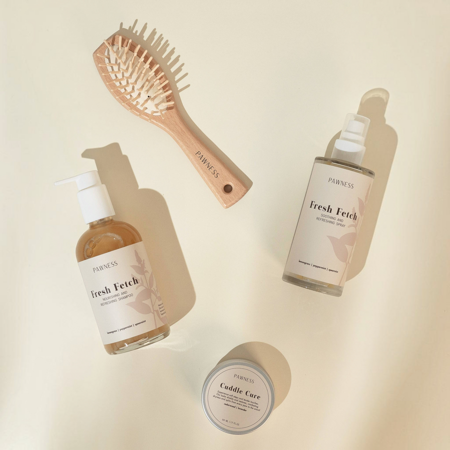 Patomia Pawness dog grooming set with Fresh Fetch spray, shampoo, wooden brush, and Cuddle Cure balm on beige surface