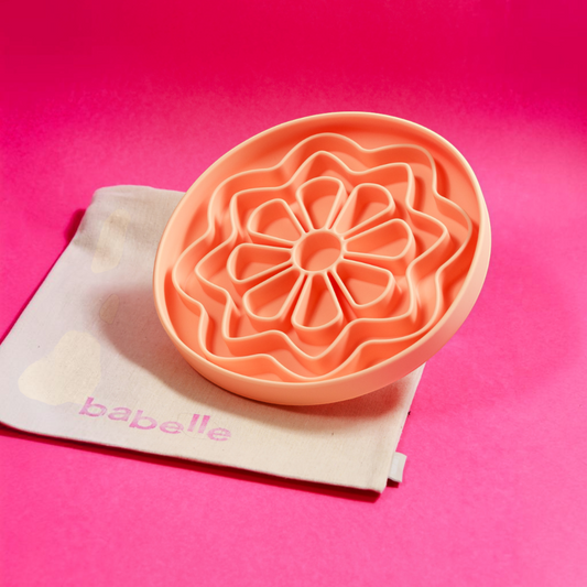 Patomia The Petal peach silicone lickmat for dogs in a flower shape on a beige cotton bag against a pink background
