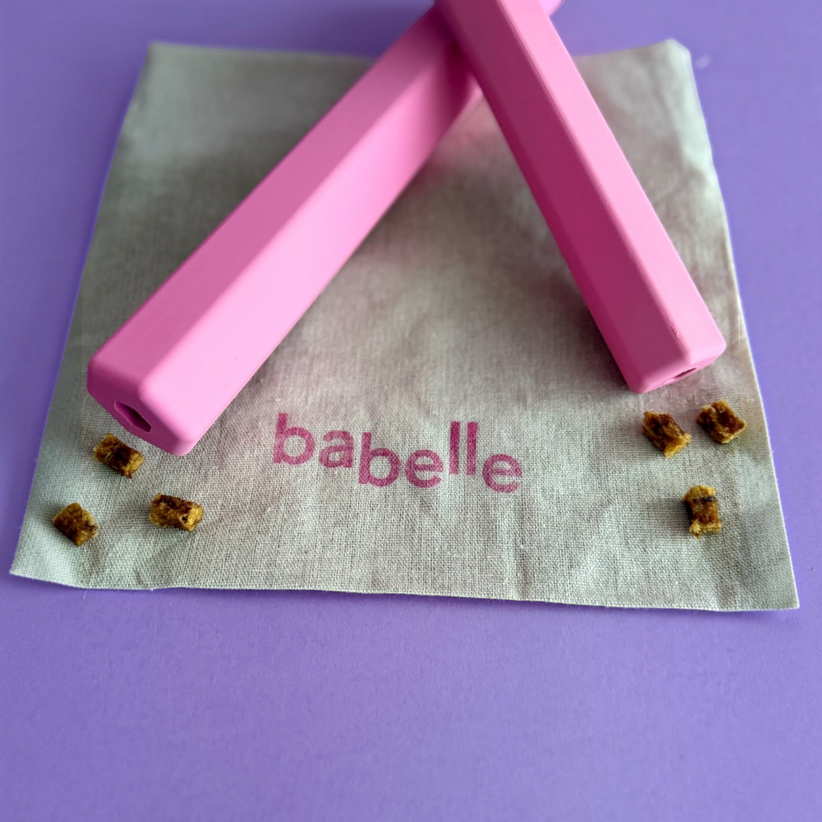 Patomia pink Treat Tube enrichment toy for dogs on a linen napkin with small treat pieces