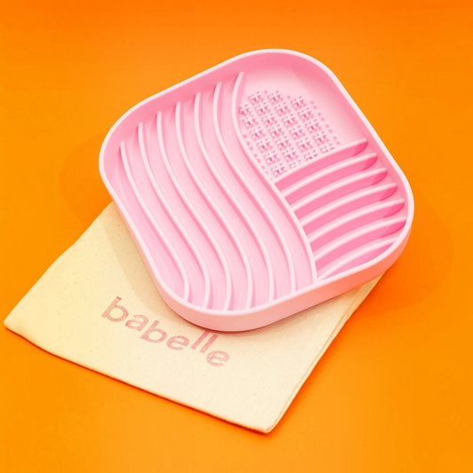 Patomia pink silicone lick mat with wavy texture for slow feeding and anxiety relief, resting on a cotton bag.