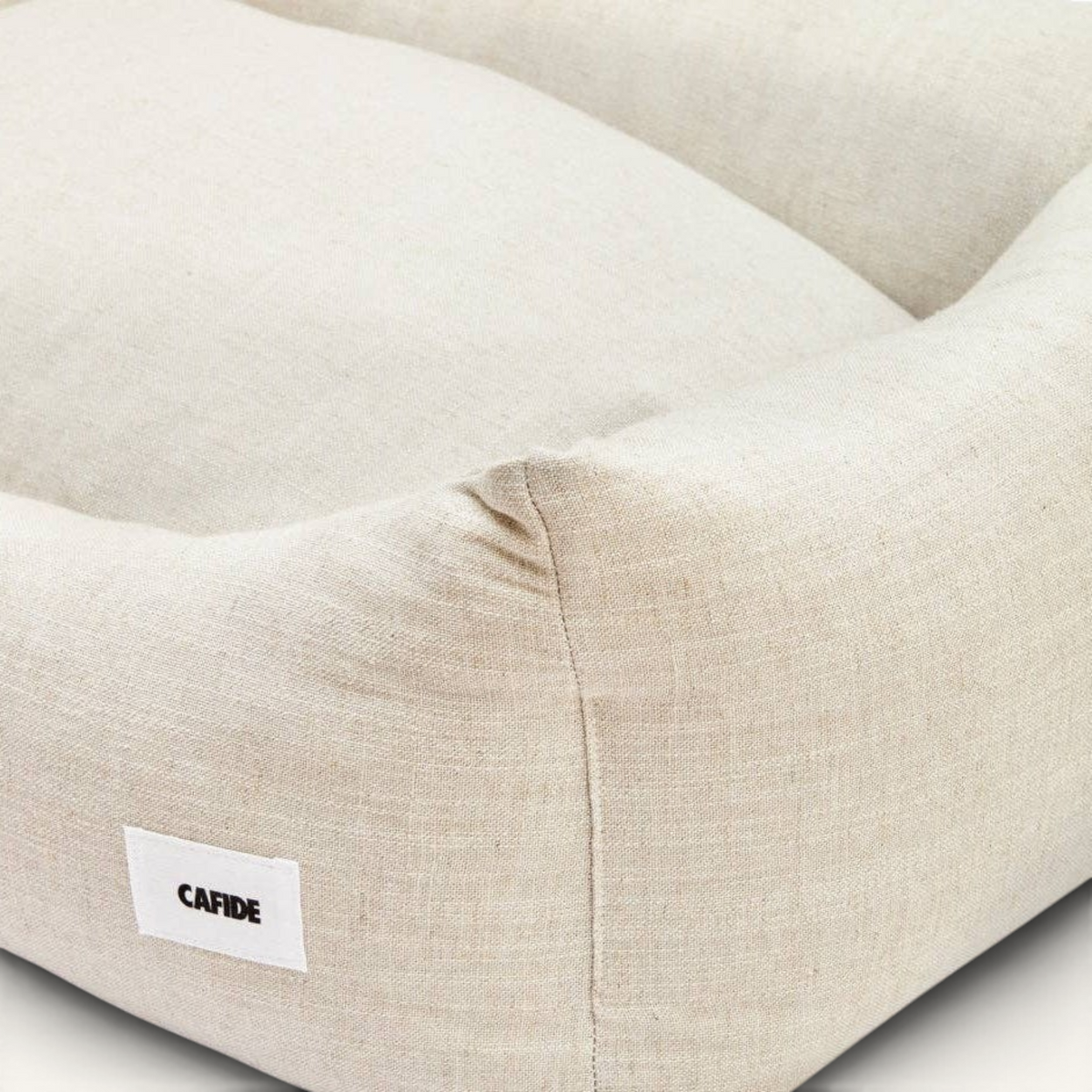 Patomia Snozy beige linen and viscose dog bed with a soft, breathable fabric and a small branded label.