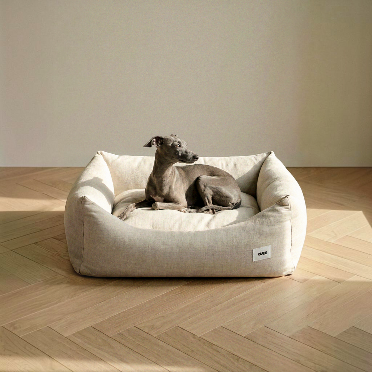 Patomia Snozy beige linen and viscose dog bed with recycled foam padding, featuring an Italian Greyhound resting.