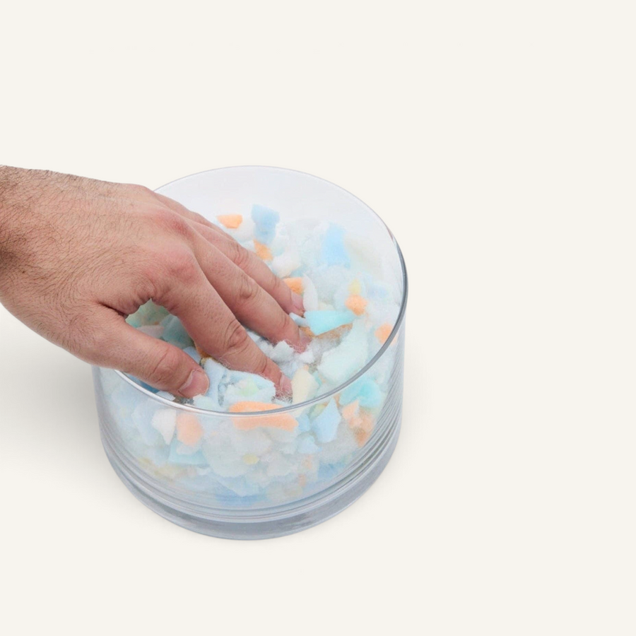 Patomia Snozy dog bed recycled foam filling inside a glass bowl being pressed by a hand