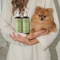 Charger l'image dans la visionneuse de la galerie, Patomia soothing dog shampoo with pistachio and oat held by a person in a robe next to a fluffy Pomeranian dog

