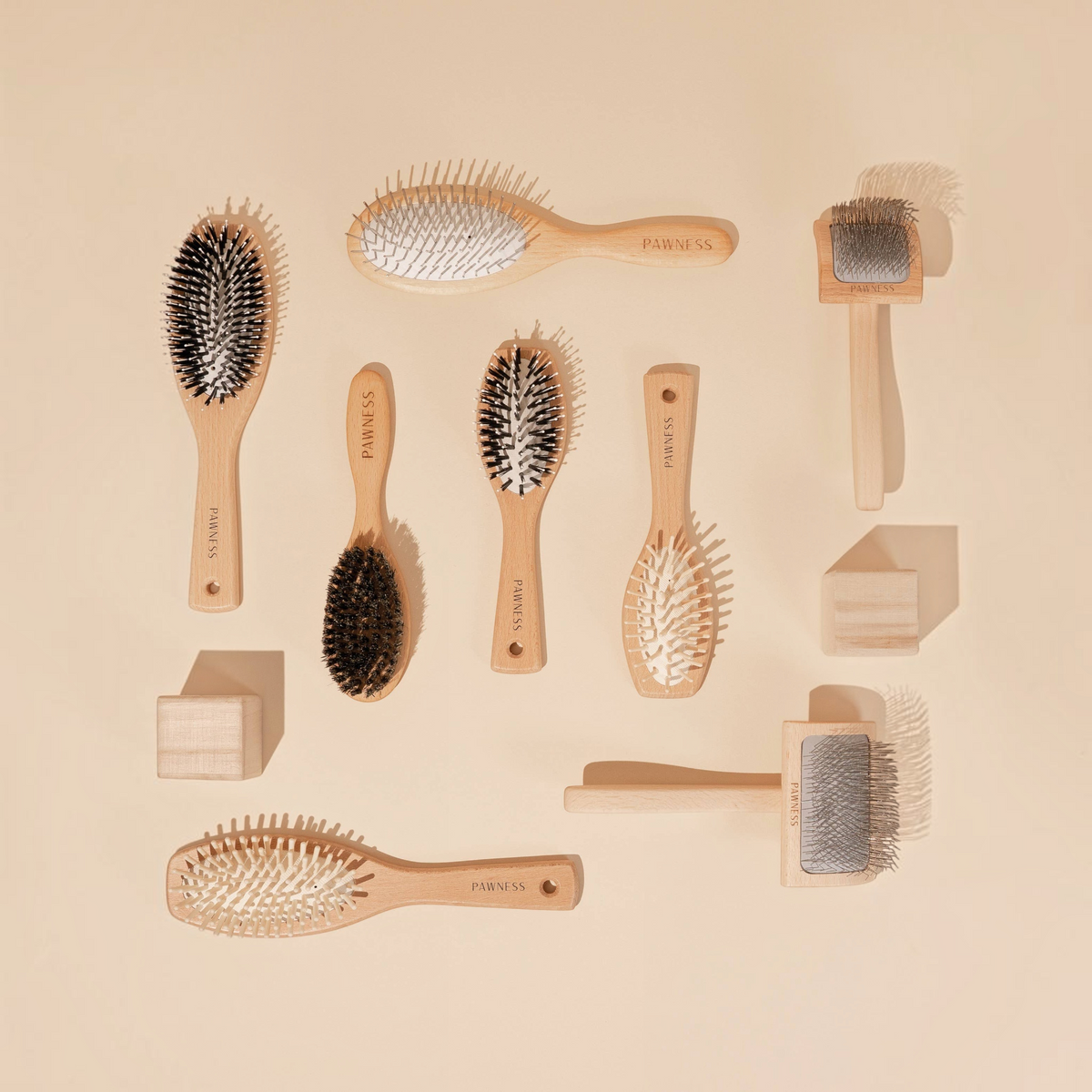 Patomia collection of wooden dog grooming brushes including slicker and bristle brushes on a beige background